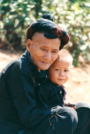 An old person holding a young child

Description automatically generated